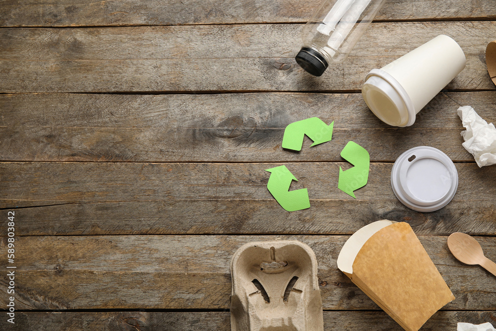 Recycling sign with garbage on wooden background