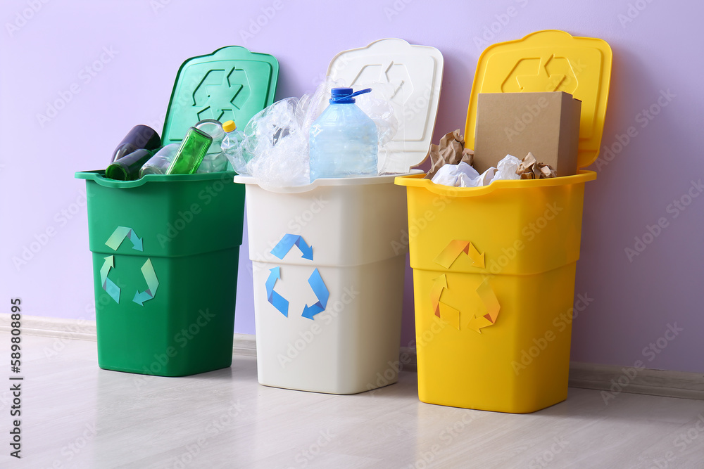 Containers with different types of garbage near lilac wall. Recycling concept