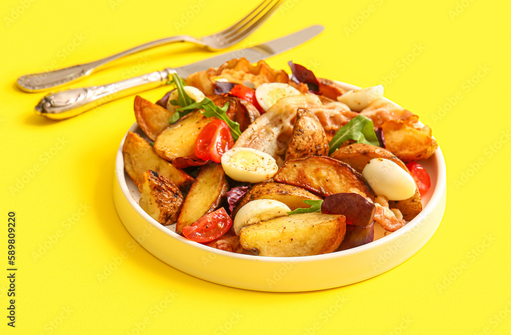 Plate of tasty potato salad with eggs, tomatoes and bacon on yellow background