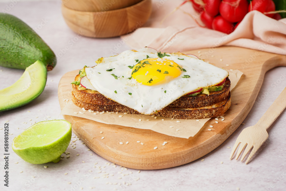 Delicious sandwich with fried egg on light background