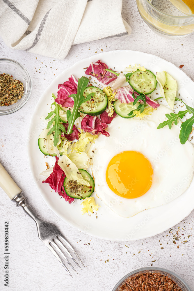 Plate with tasty fried egg and salad on light table