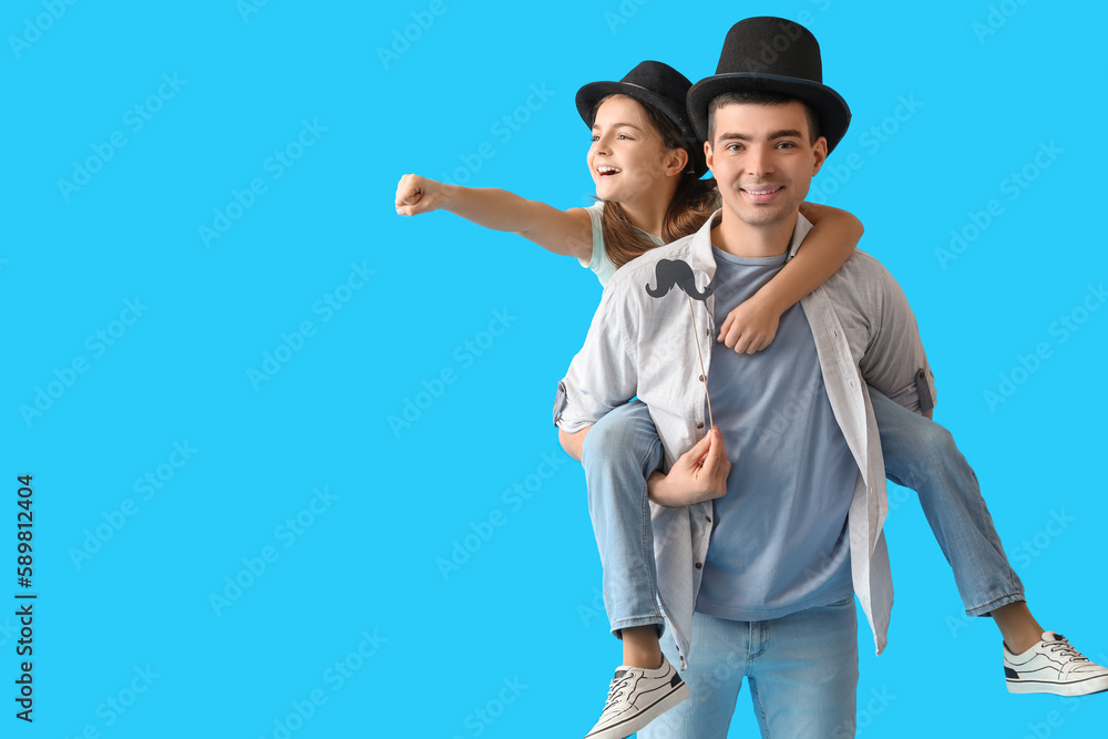 Portrait of father and his little daughter with paper mustache on light blue background