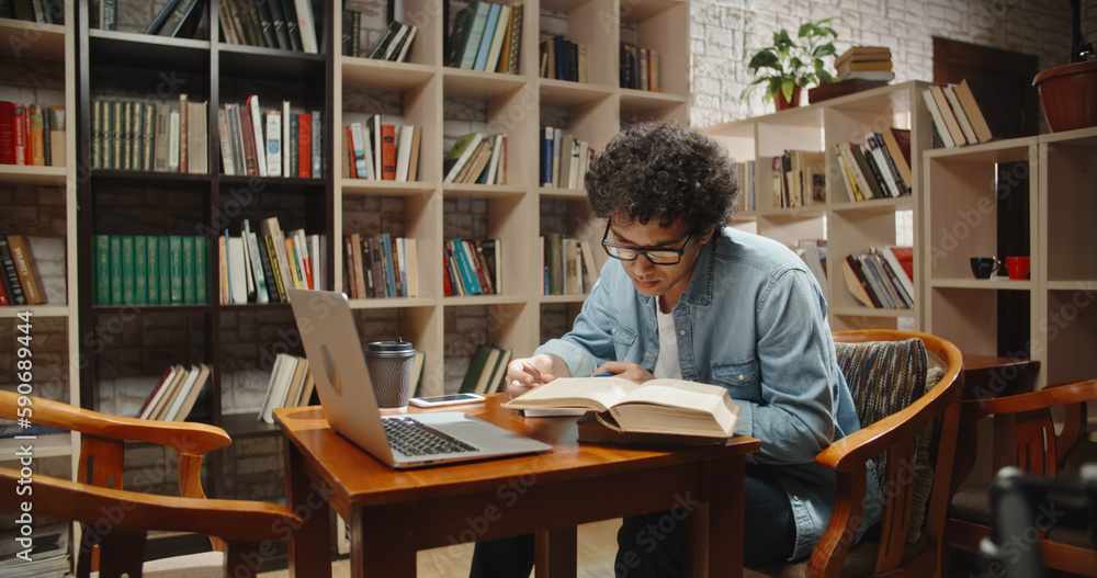 Asian student doing research in library using laptop in books, making a project and preparing for ex