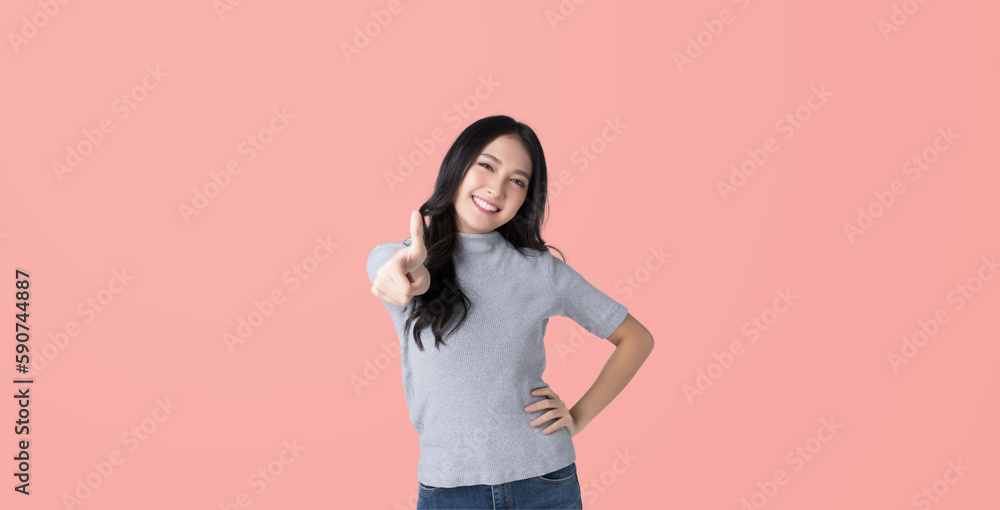 Young Asian woman showing thumbs up sign on hand isolated pink color background