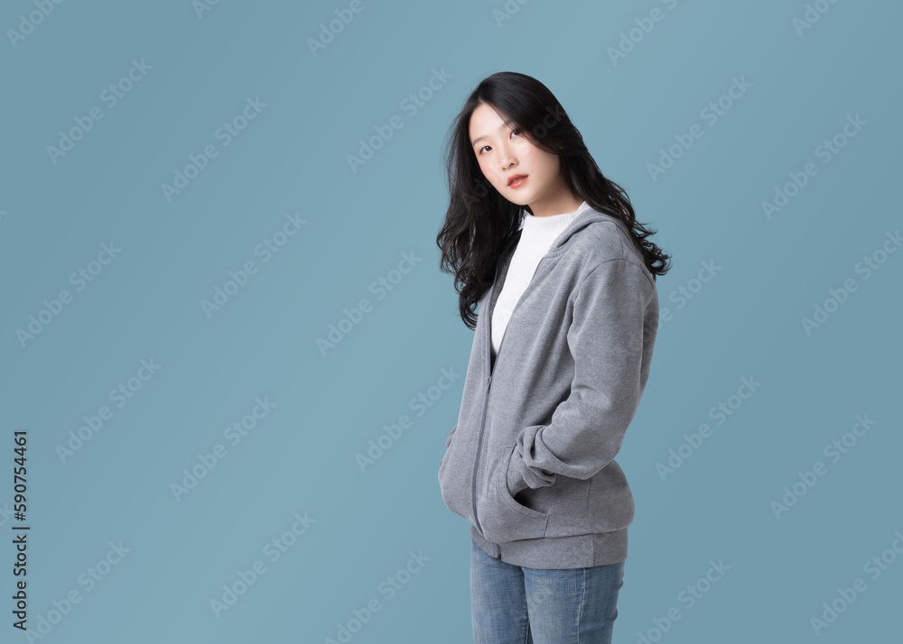 Portrait beautiful Asian woman in hoodie sweatshirt and blue jeans isolated over cyan background