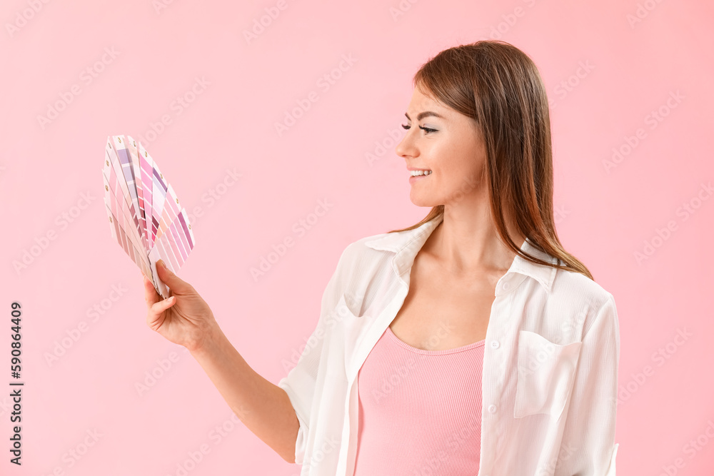 Beautiful woman with paint color palettes on pink background