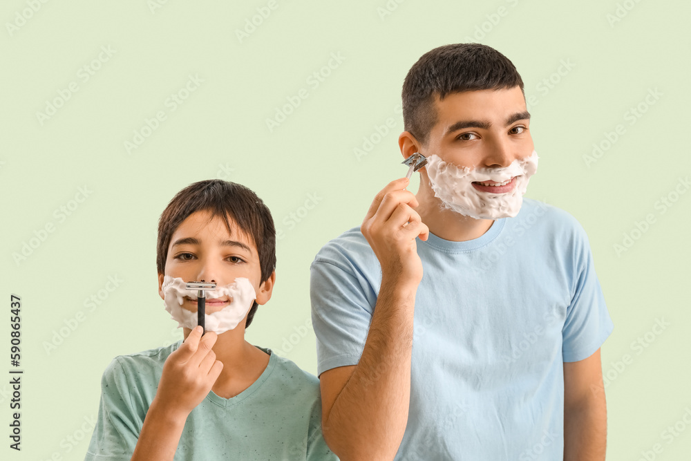 Man and his little son shaving against light color background