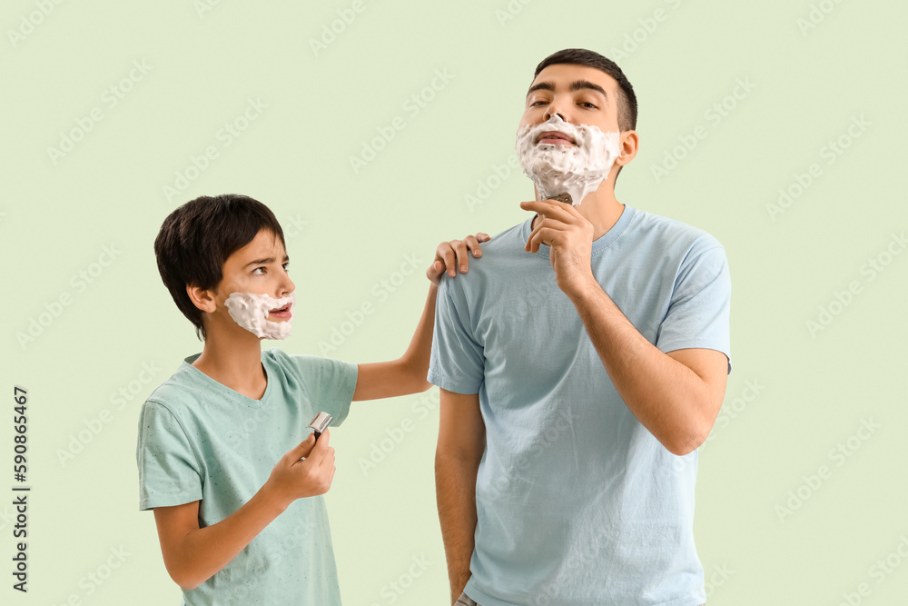 Man and his little son shaving against light color background