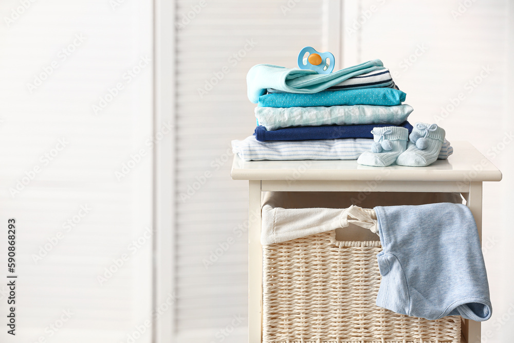 Baby clothes and pacifier on shelf unit in room