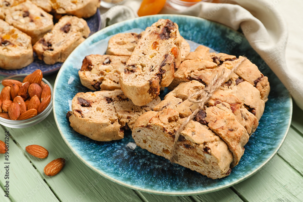 Plate with tasty biscotti cookies and almonds on color wooden table, closeup