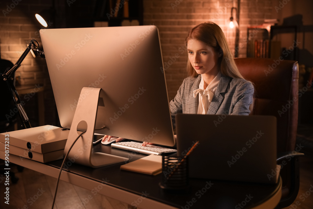 Female programmer working with computer in office at night