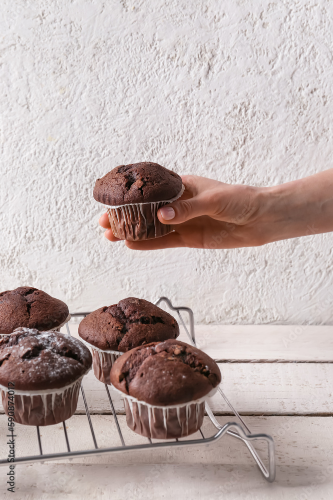 Woman holding tasty chocolate cupcake at table