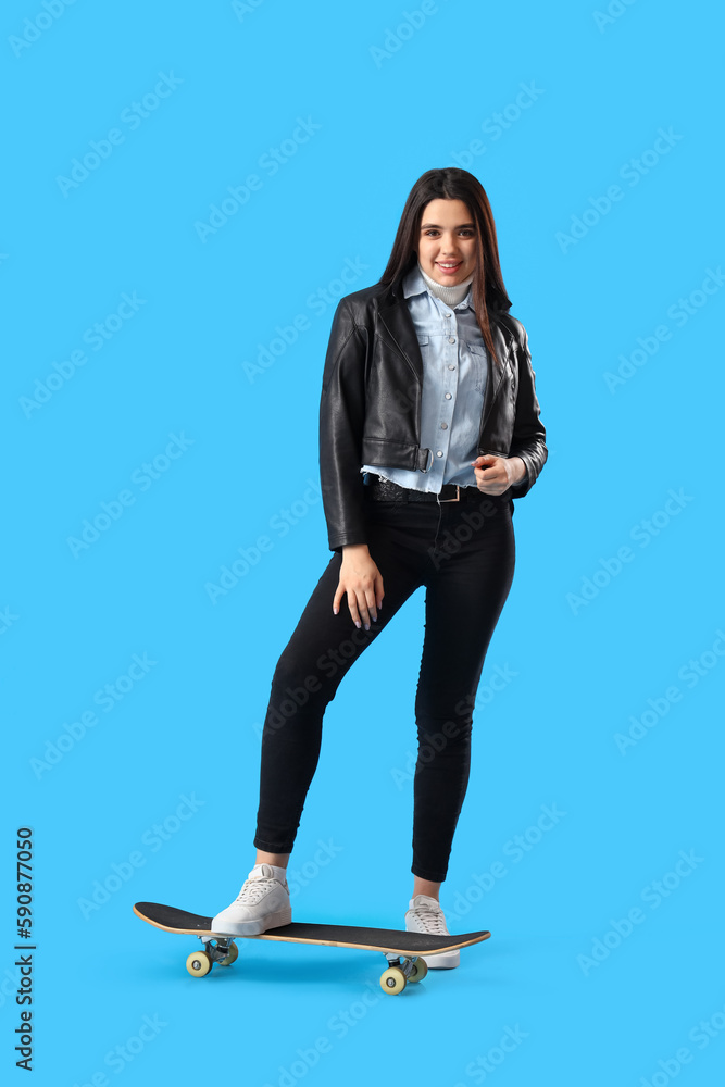 Stylish young woman with skateboard on blue background