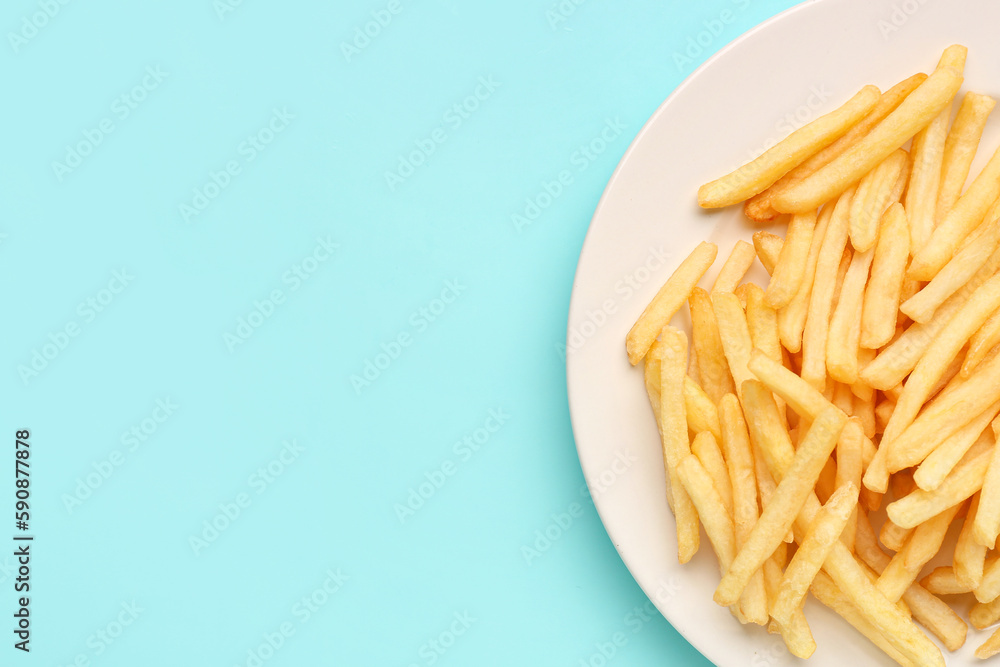 Plate with tasty french fries on light blue background