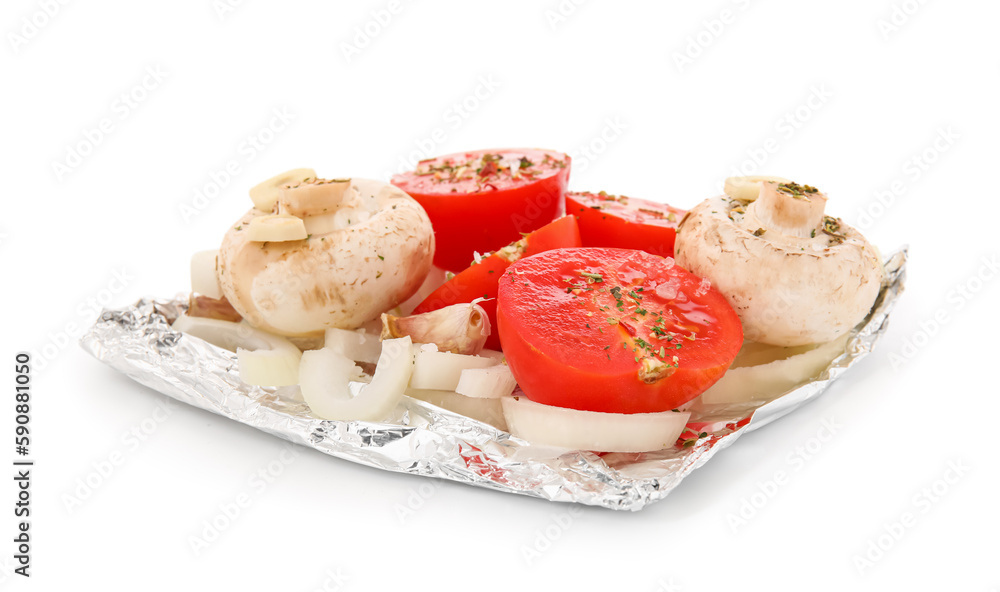 Aluminium foil with raw vegetables on white background