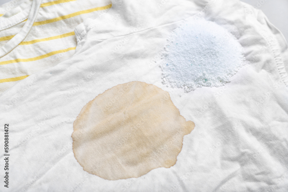 Laundry detergent with stained clothes on light background, closeup