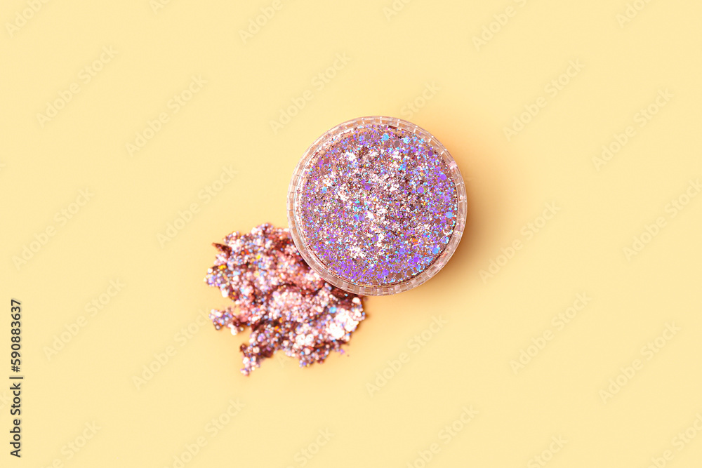 Jar of glitter with stroke on yellow background, closeup