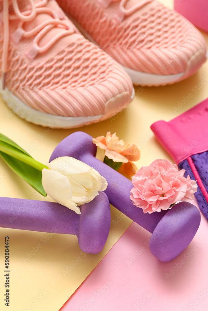 Dumbbells with spring flowers on color background, closeup