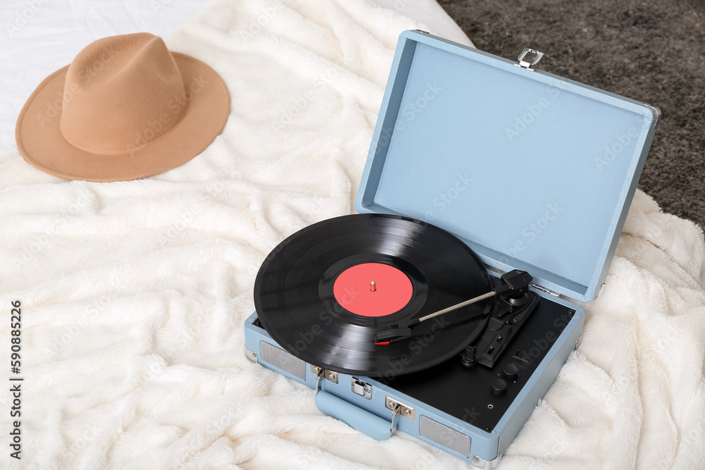 Record player with vinyl disk on bed in room