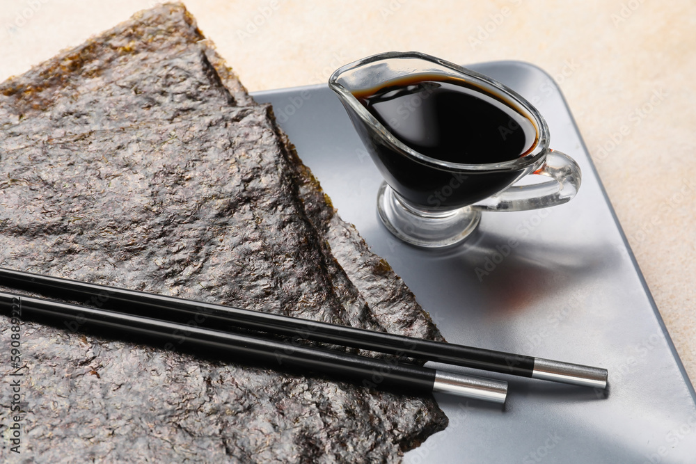 Plate with nori sheets and sauce on light background, closeup