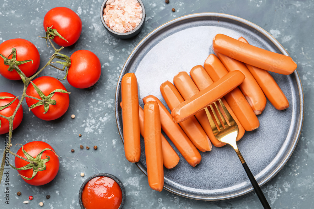 Plate with tasty sausages and fresh tomatoes on blue background