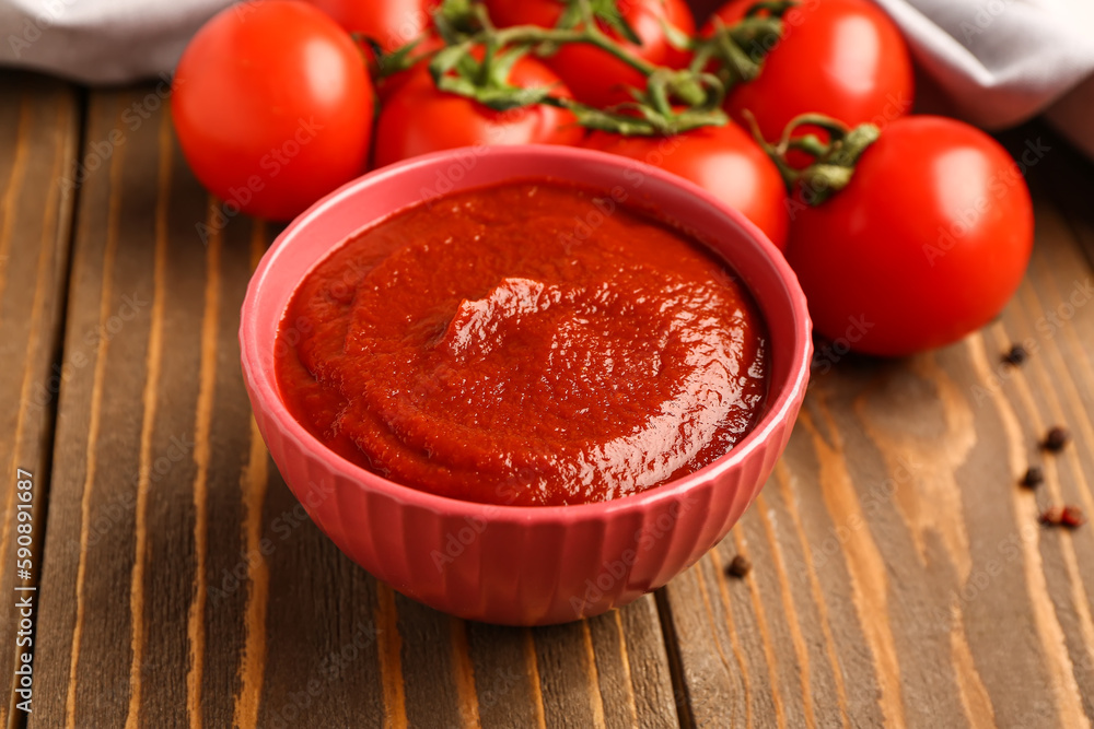 Bowl with tasty tomato paste on wooden background, closeup