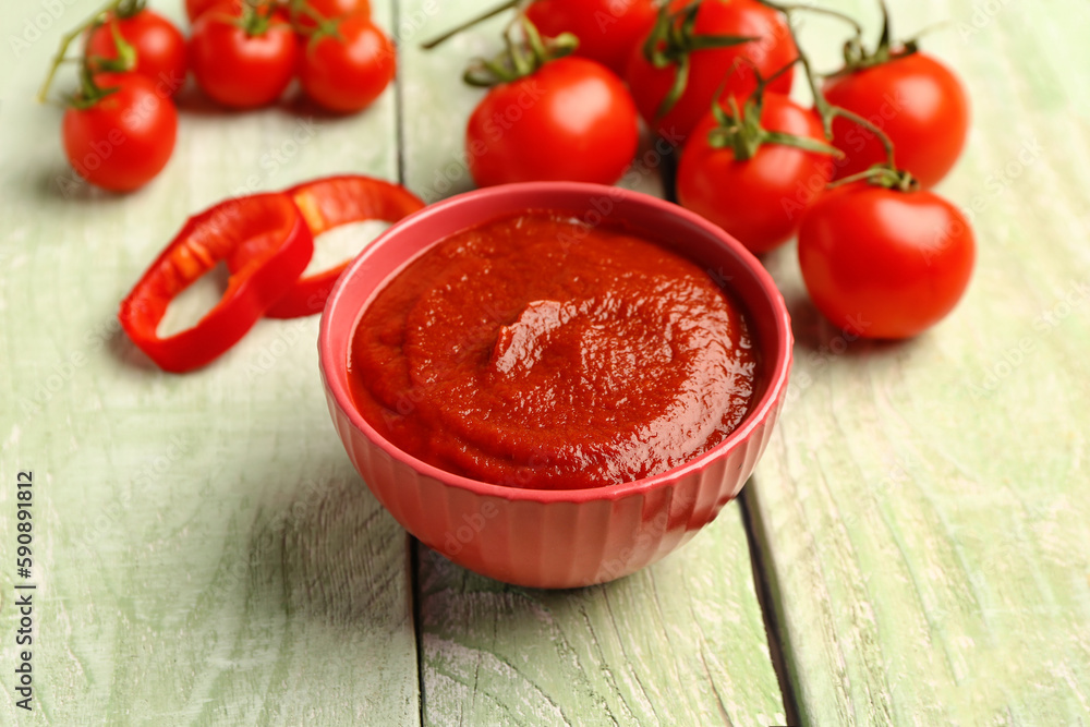 Bowl with tasty tomato paste on light wooden background, closeup