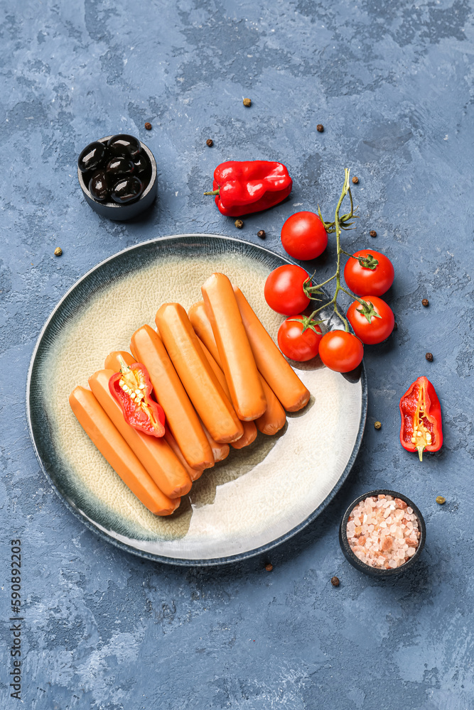 Plate with sausages, tomatoes and olives on blue background