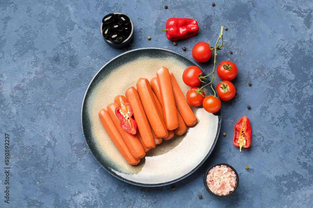 Plate with sausages, tomatoes and olives on blue background