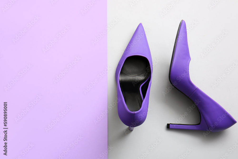 Pair of stylish high heeled shoes on color background