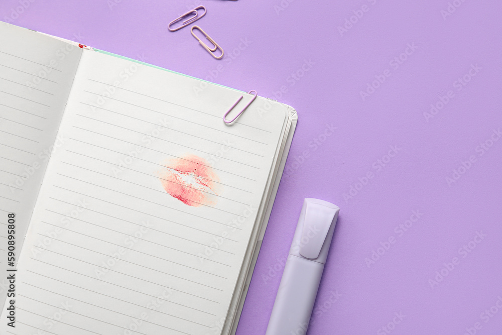 Notebook with lipstick kiss mark and stationery on lilac background, closeup