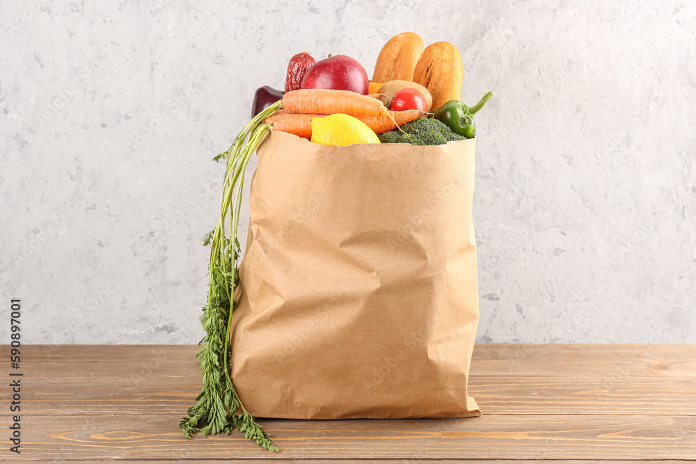 Paper bag with vegetables and fruits on wooden table