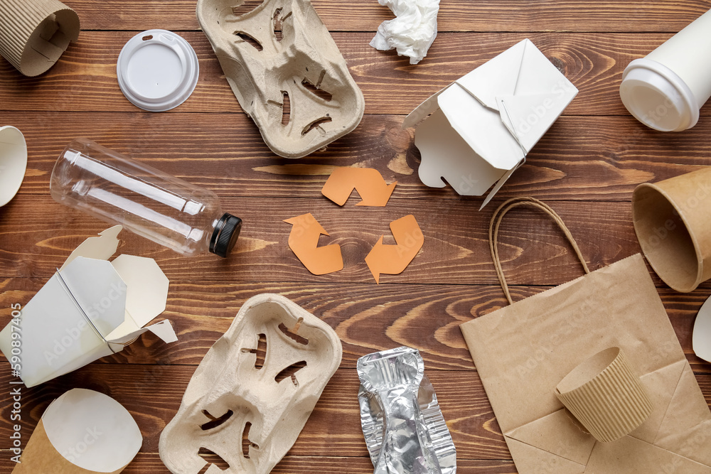 Recycling sign with garbage on wooden background