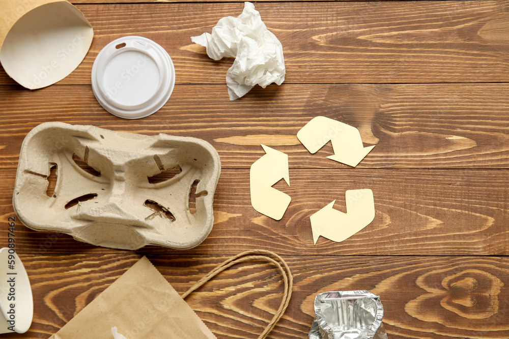 Recycling sign with garbage on wooden background