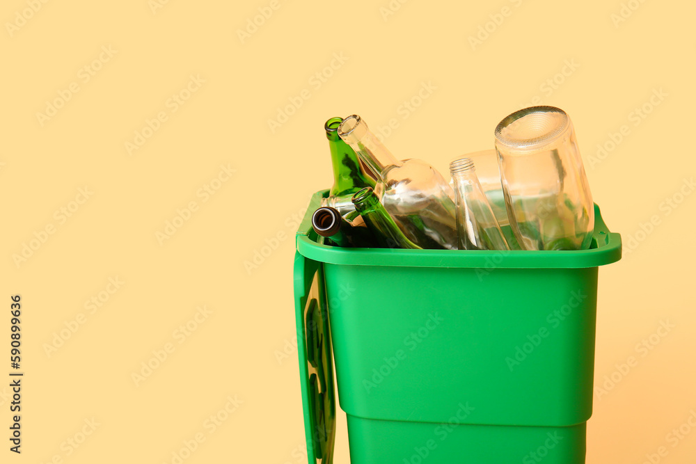 Container for garbage with glass bottles on beige background. Recycling concept