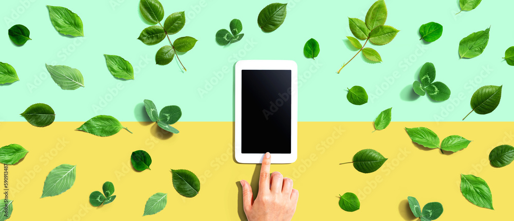 Green leaves with a tablet computer - flat lay