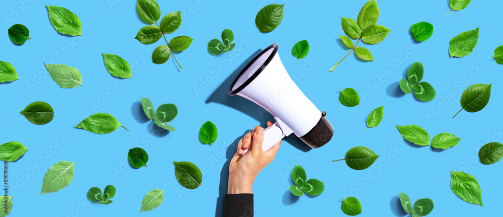 Person holding a megaphone with green leaves - flat lay