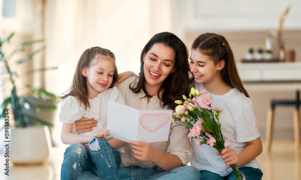 Daughters giving mother bouquet of flowers.