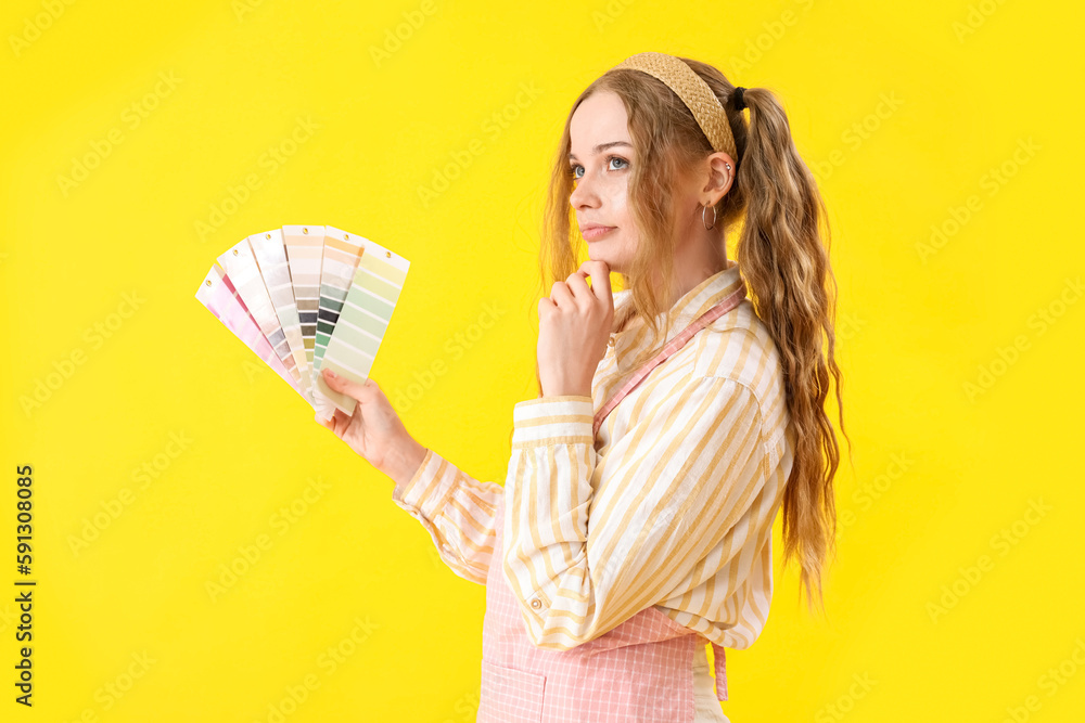 Thoughtful female artist with paint color palettes on yellow background