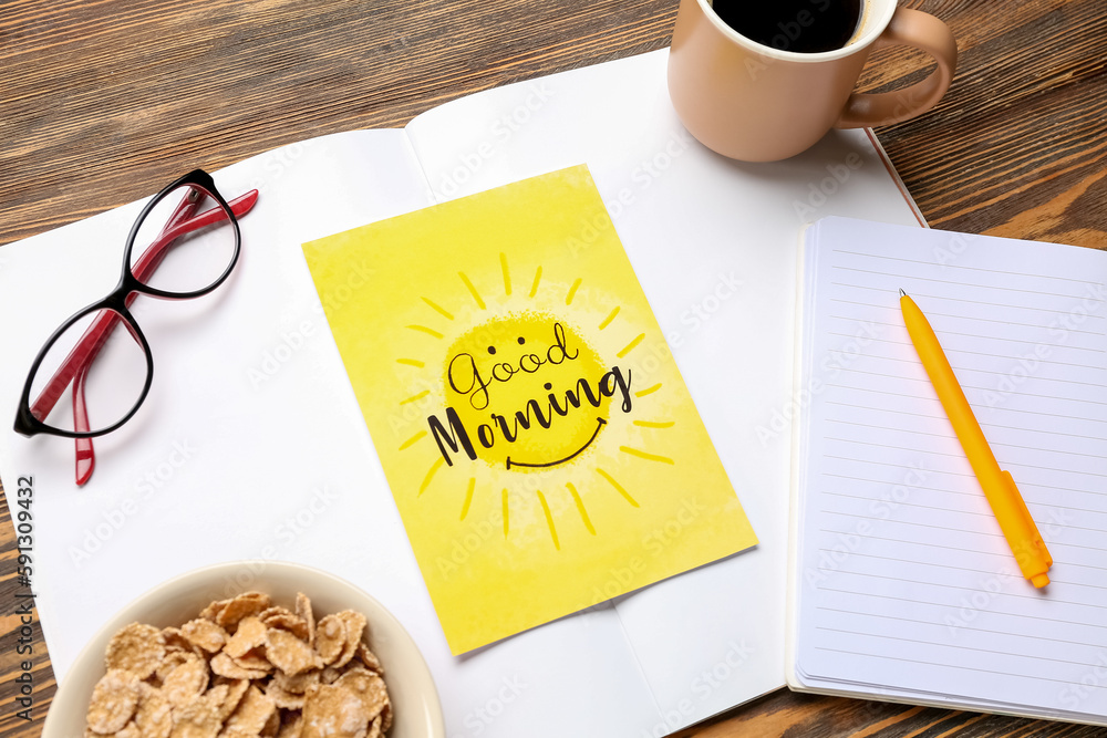 Card with text GOOD MORNING, eyeglasses and notebooks on wooden table