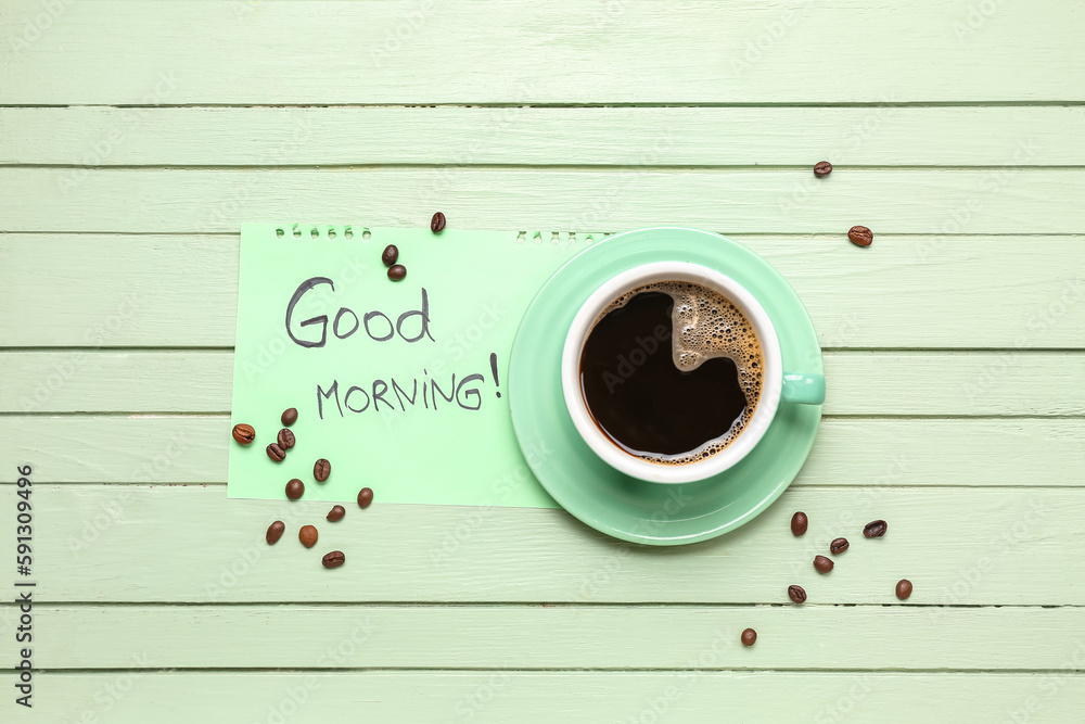 Cup of coffee, beans and paper with text GOOD MORNING on color wooden background