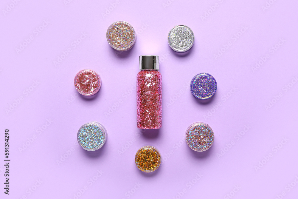 Bottle with jars of glitter on lilac background