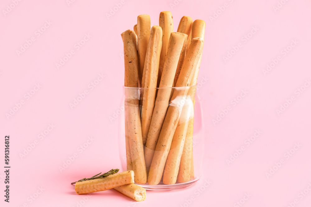 Jar with tasty Italian Grissini on pink background