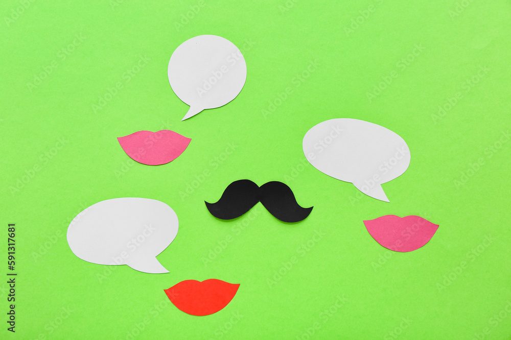 Paper lips and mustache with speech bubbles on green background. Dialogue concept