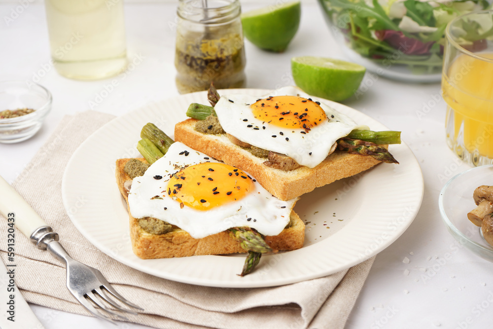 Delicious sandwiches with fried eggs and asparagus on light background