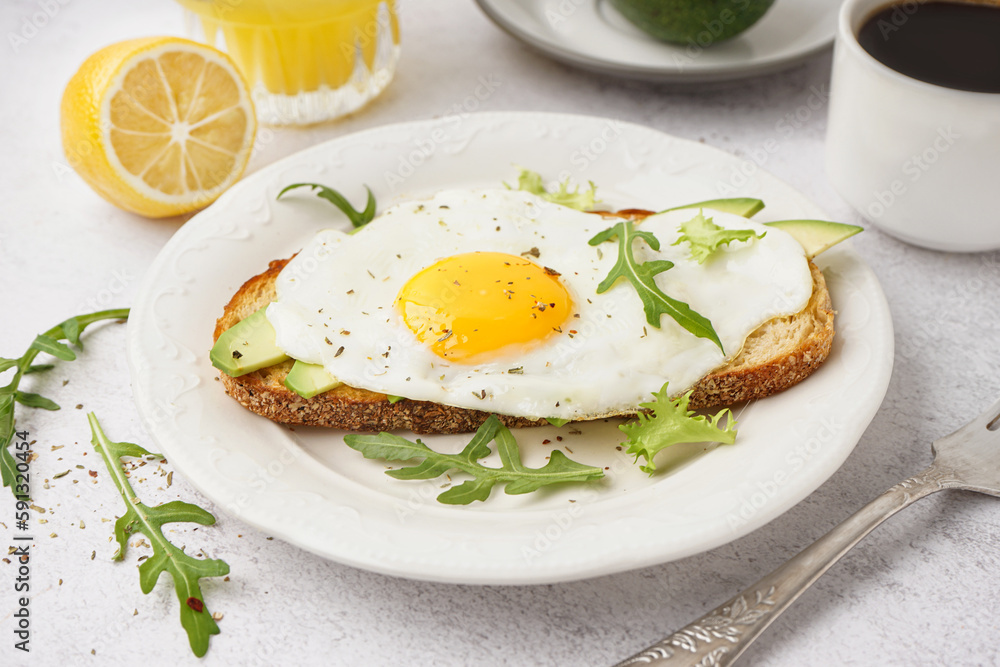 Delicious sandwich with fried egg, arugula and avocado on light background