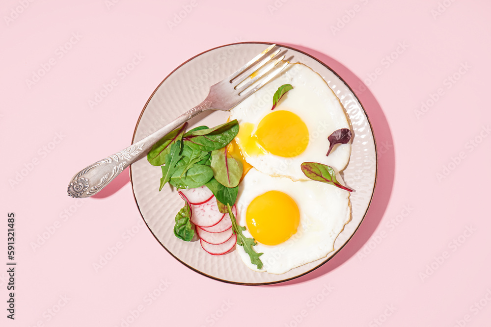 Plate with tasty fried eggs, radish and spinach on pink background