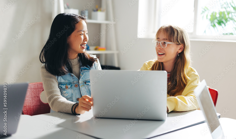 Two happy female students learning together in a coding class