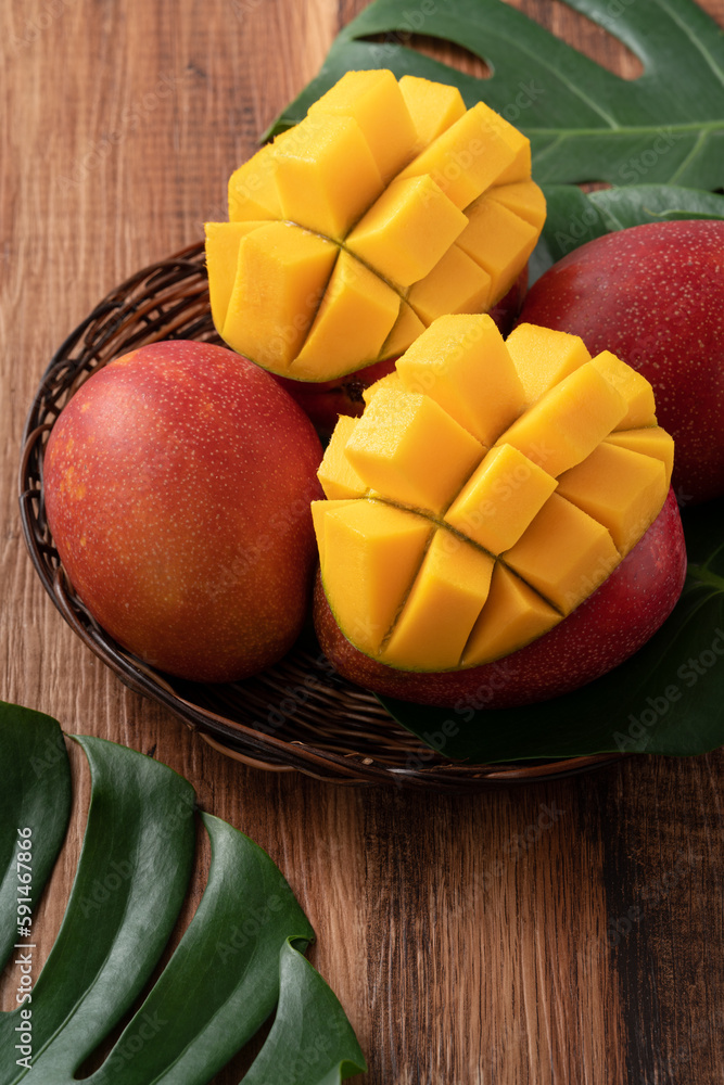 Fresh mango fruit with leaves over dark wooden table background.