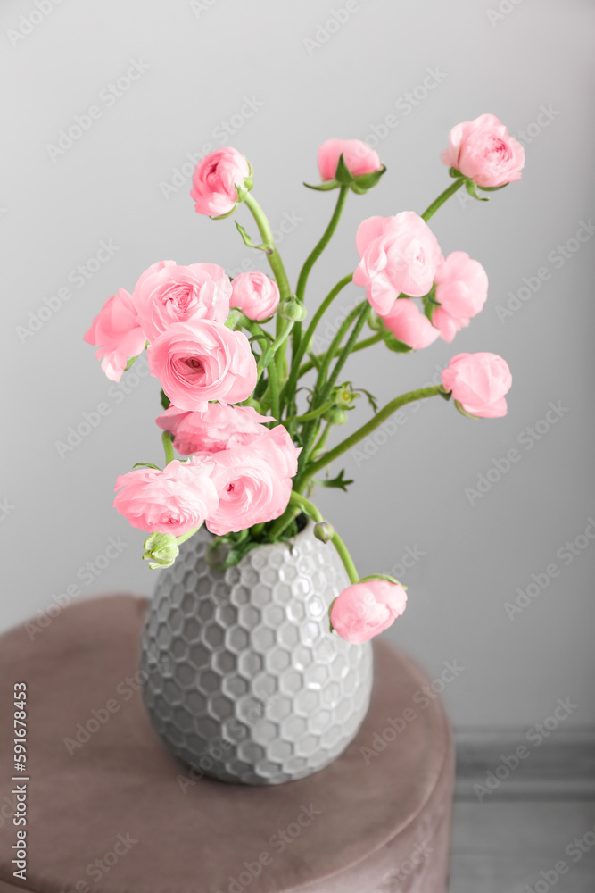 Vase with pink ranunculus flowers on table in room